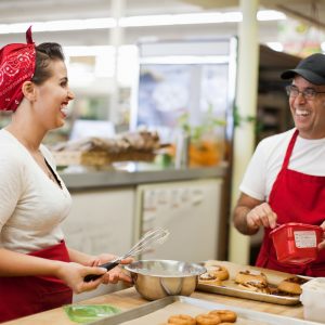 Young woman and man laughing in commercial kitchen